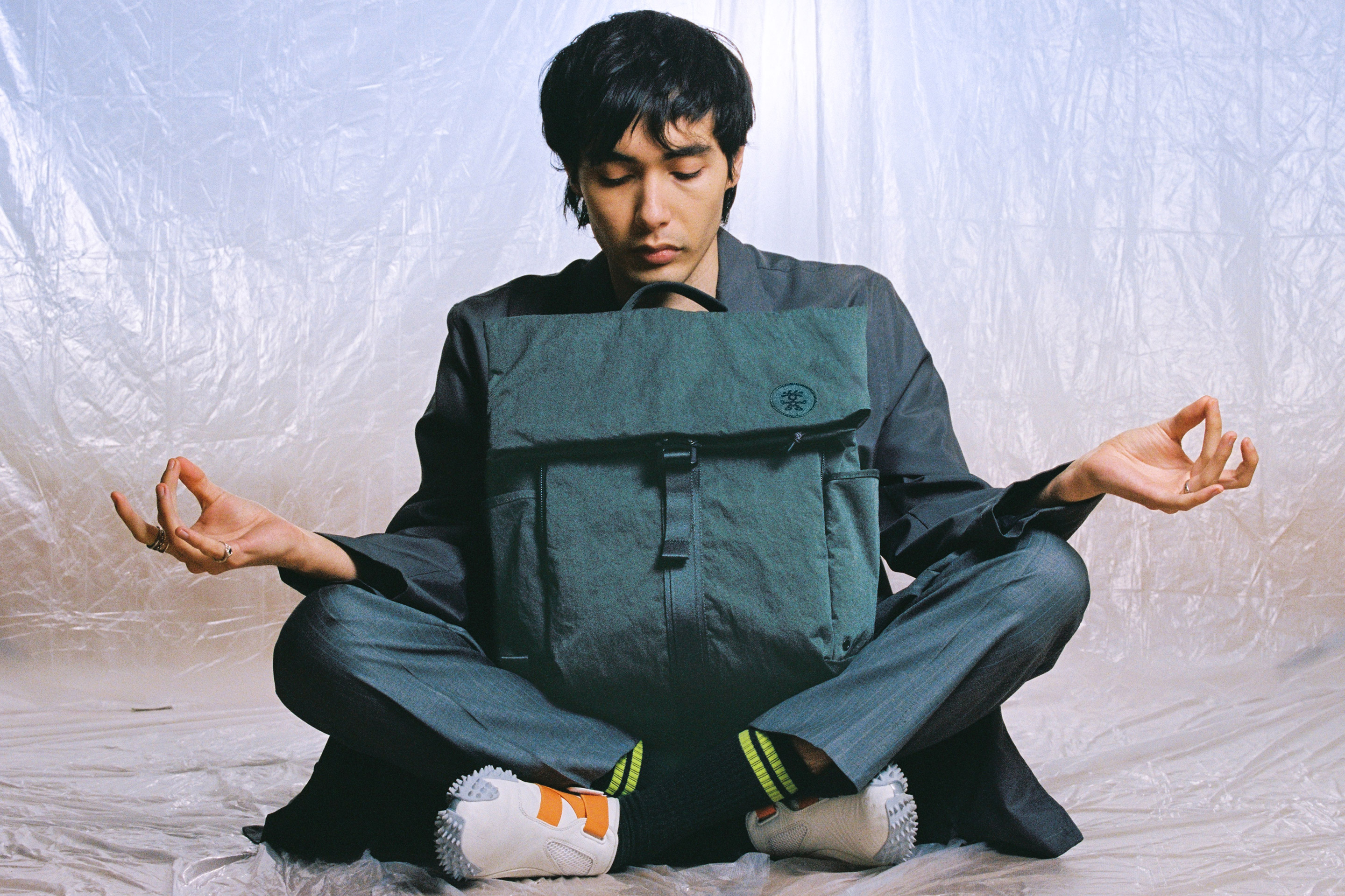 Model meditating with green KONBU backpack