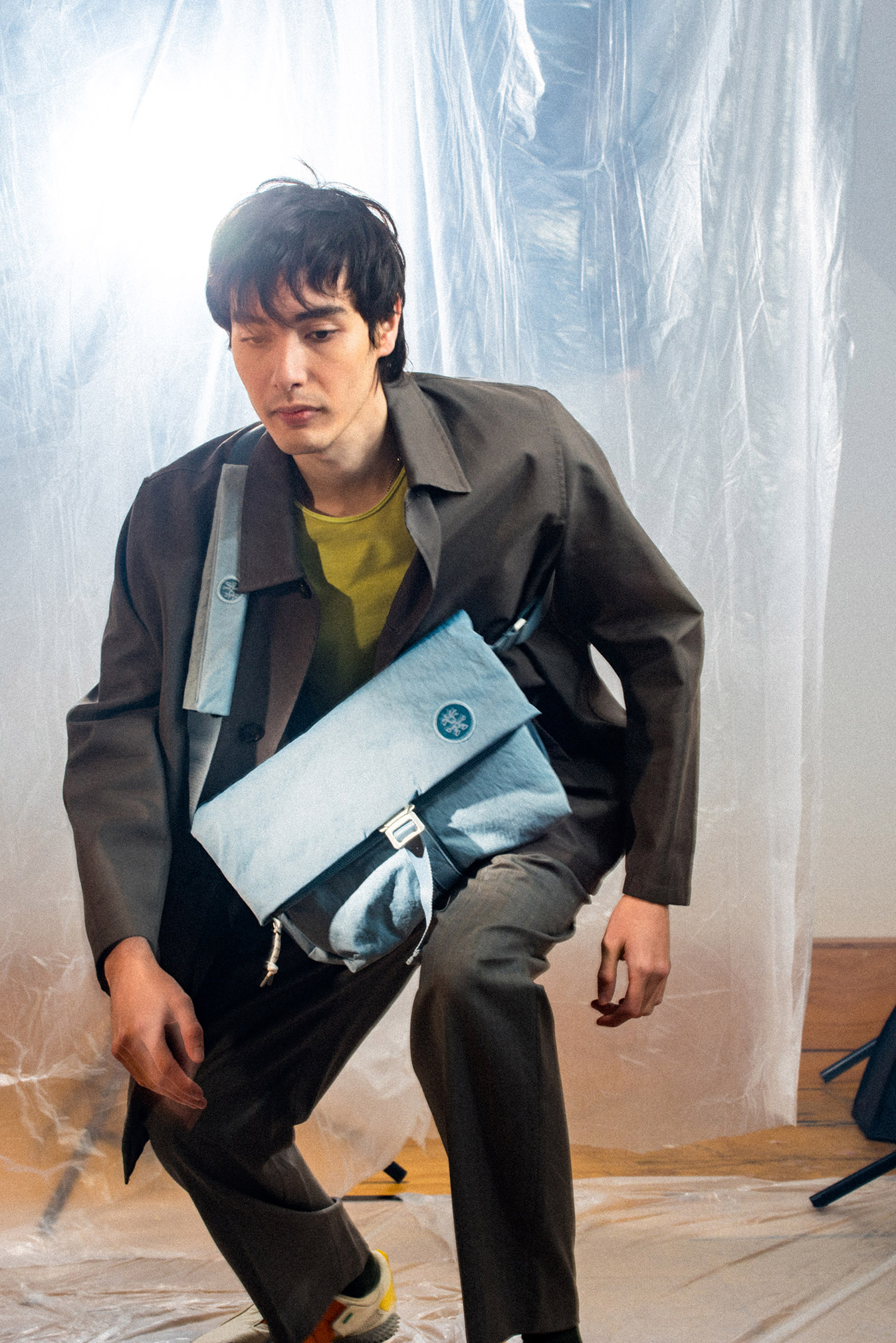 Model crouching with light blue KONBU messenger bag
